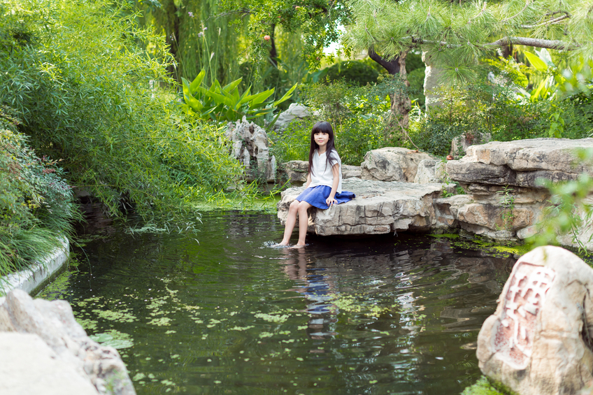 chinese sweet and innocent little girl, in the park's pond barefoot playing in the water